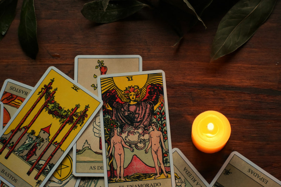 A lit candle beside a stack of tarot cards on a wooden table, ready for a Scorpio season reading