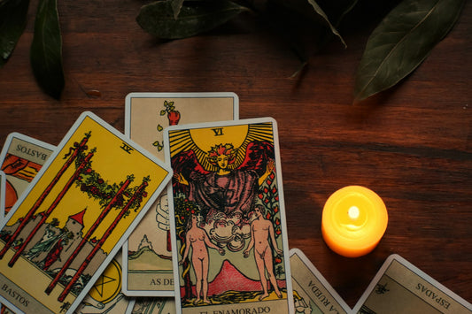 A lit candle beside a stack of tarot cards on a wooden table, ready for a Scorpio season reading