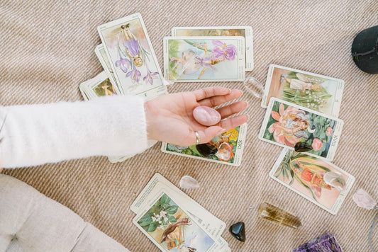 A person holding a crystal over tarot cards