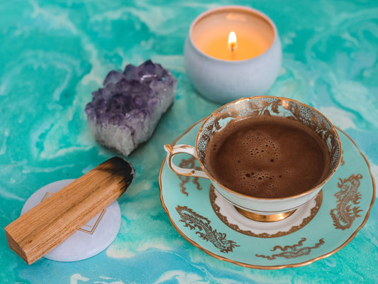 A coffee cup with a crystal and a palo santo stick next to it